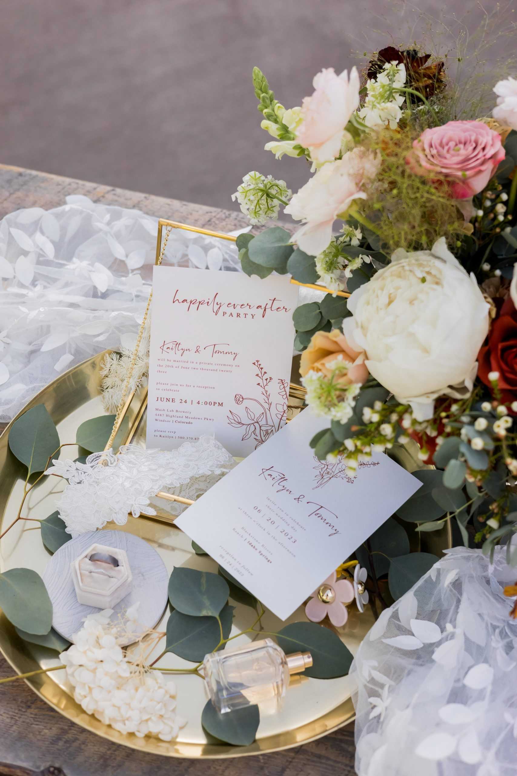 Wedding invites, a bouqet of flowers, and other wedding details on a table at a Colorado wedding