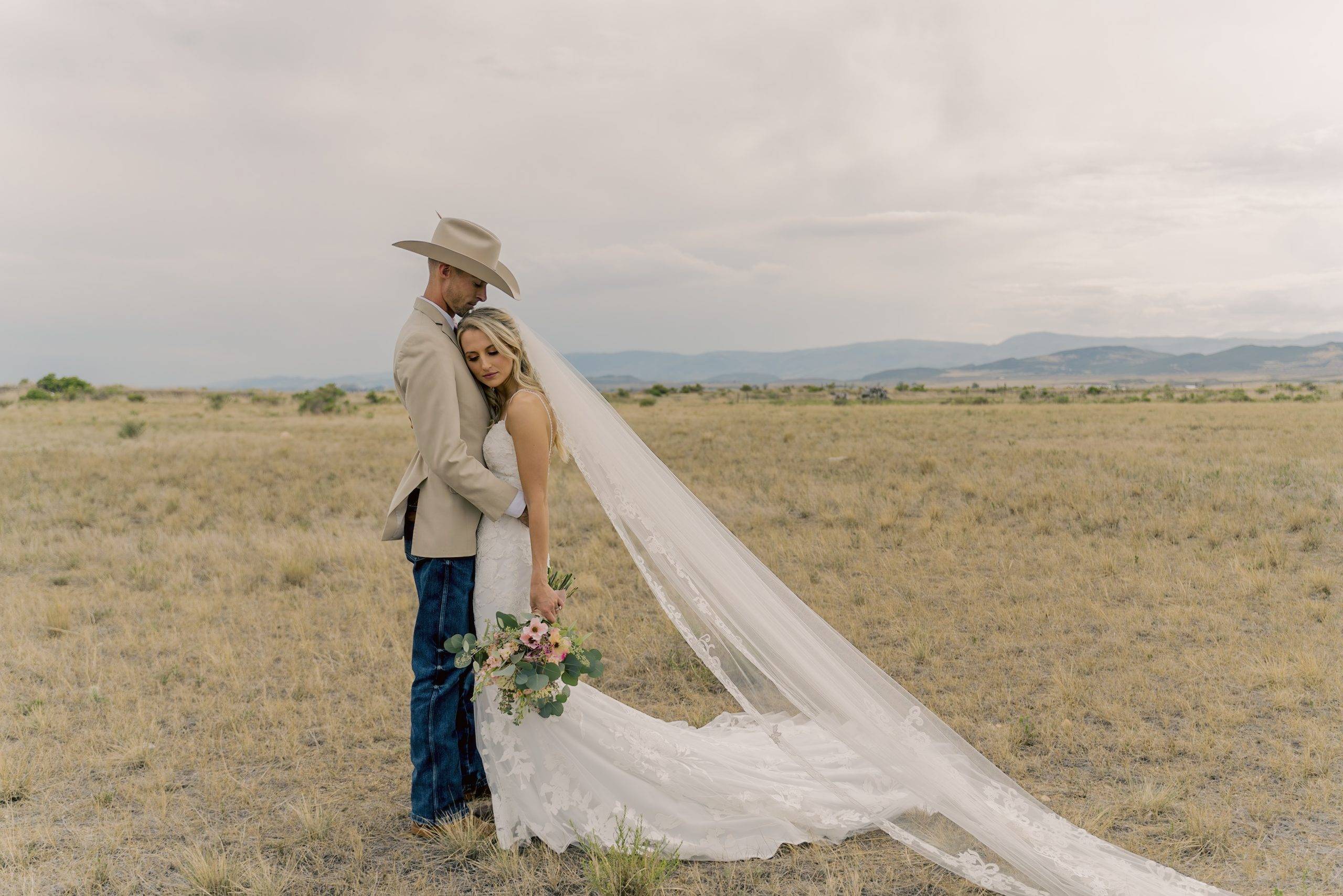 Bride and groom, embracing each other in a field in the foothills of Colorado