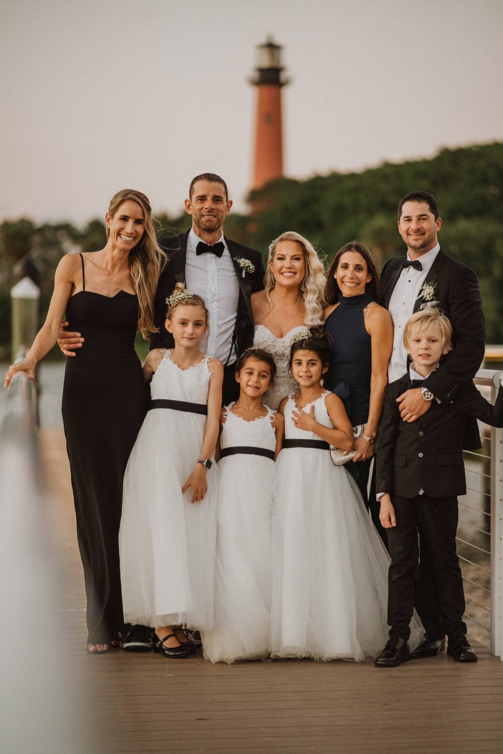 Family on a pier with bride and a light house in the beackground in Jupiter, Florida