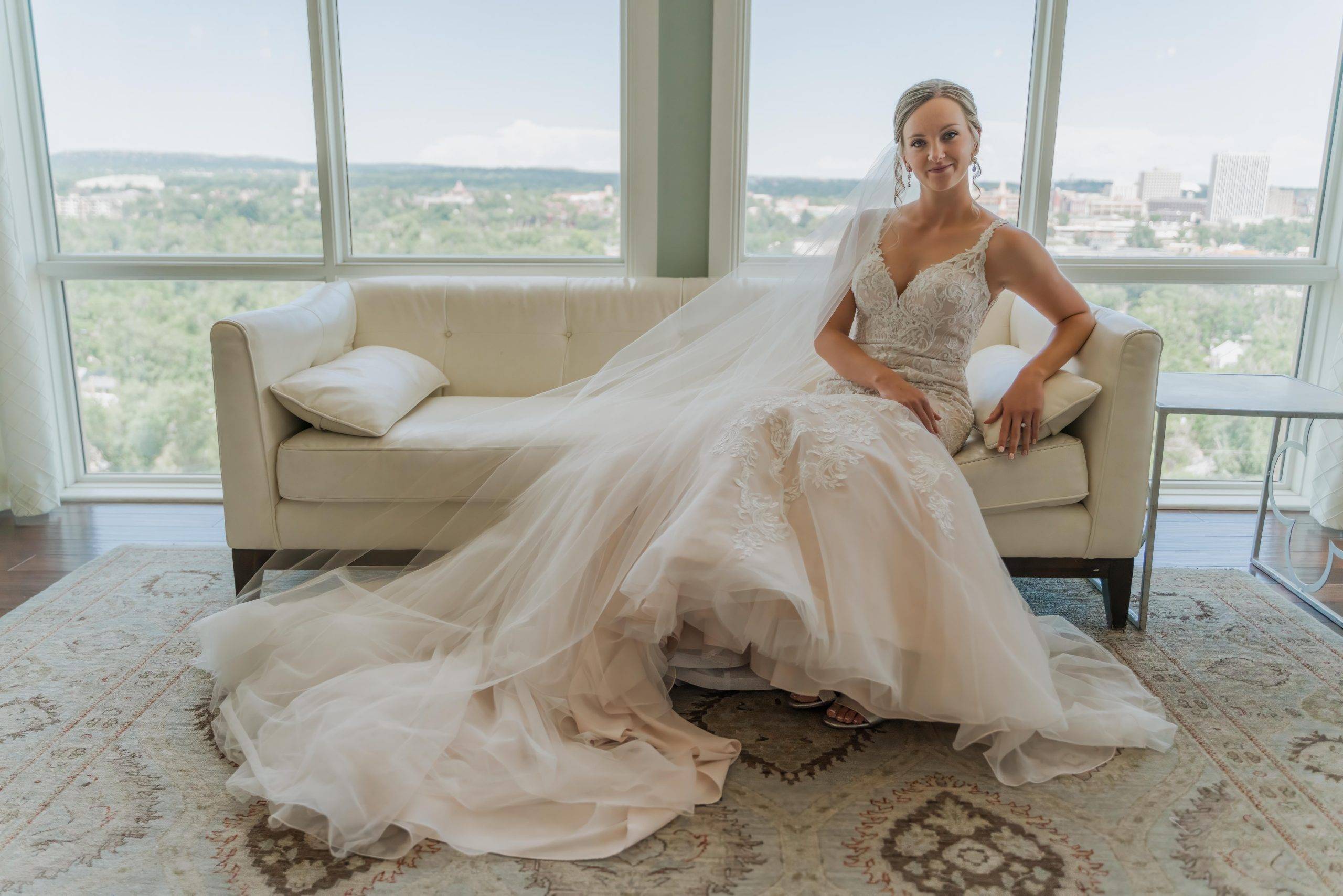 A bride sitting in her wedding dress on a white couch in Colorado Springs, Colorado