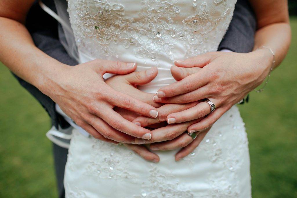 A bride and grooms hands with their wedding rings