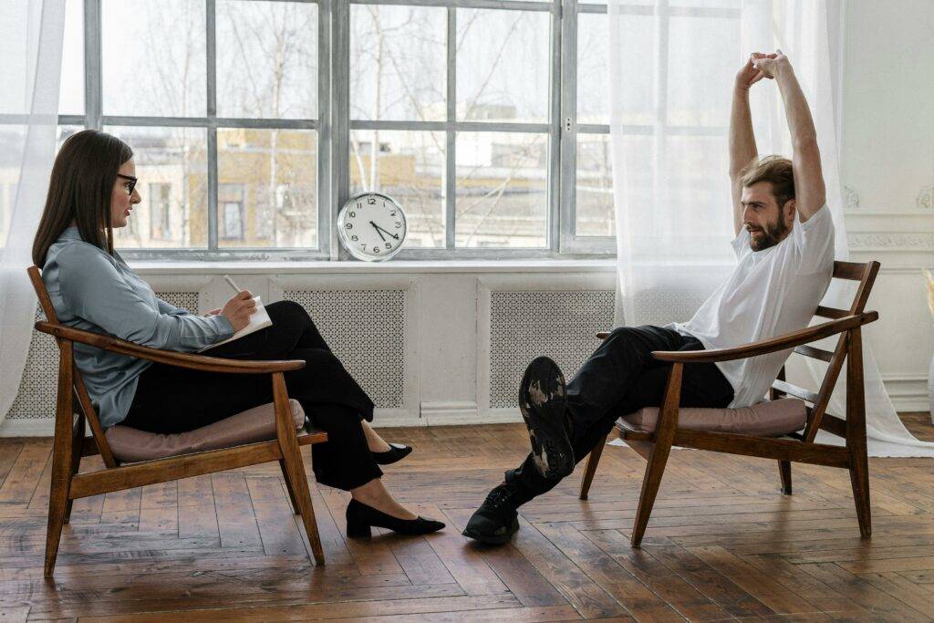 a man stretches while talking with a woman about her day in front of glass windows