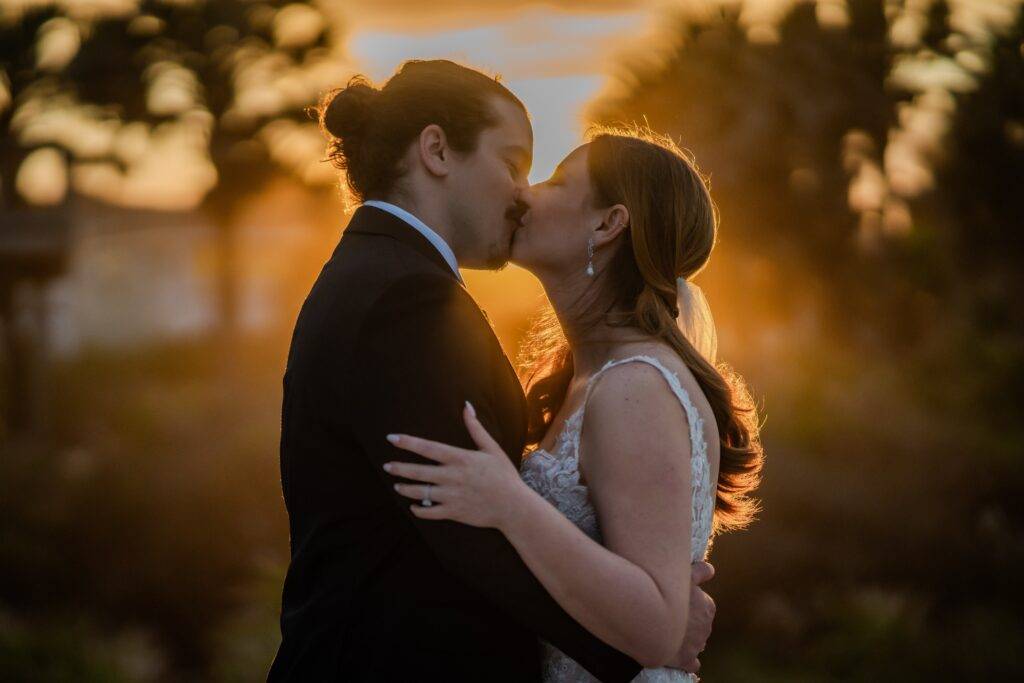 bride and groom kissing with a romantic golden sun light wrapped around them in Florida